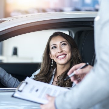 toco car warranty corp vehicle service contracts price cost woman behind the wheel in car happy signing vehicle service contract